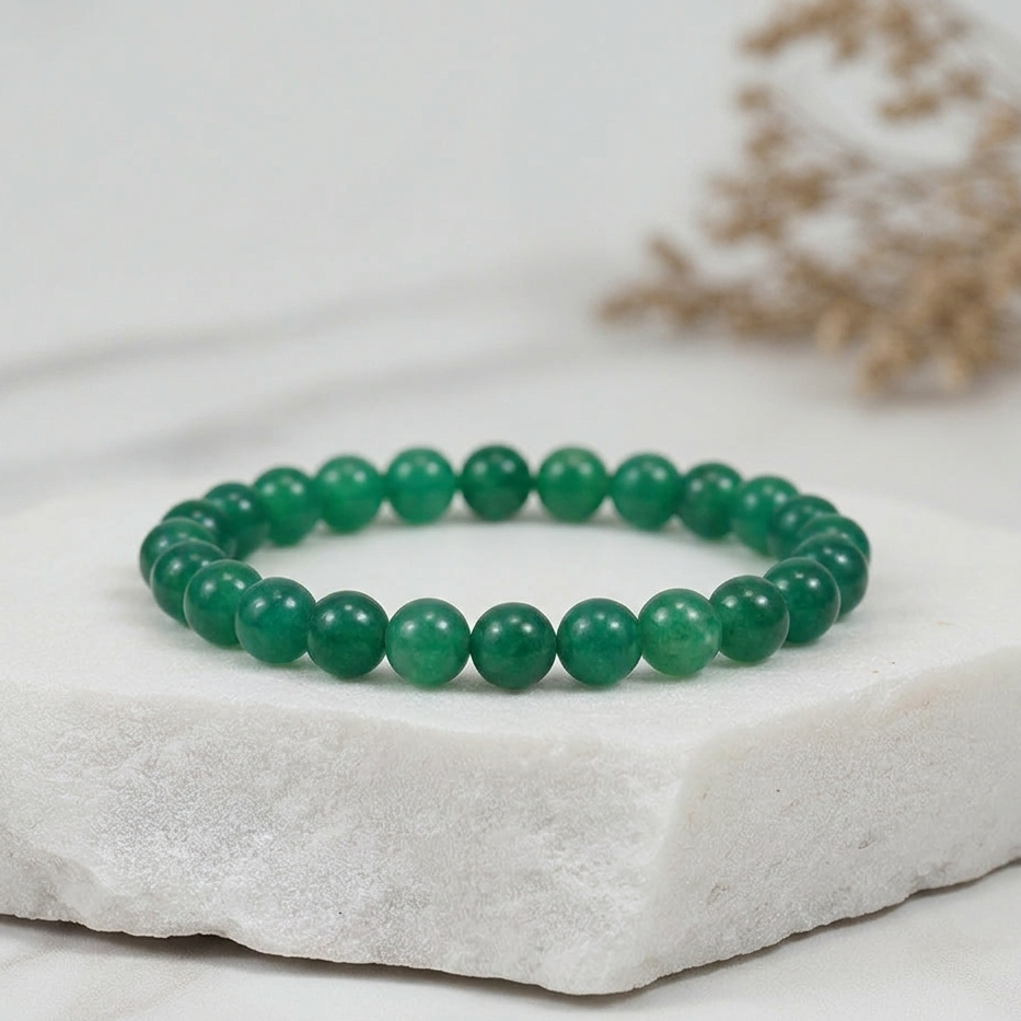 Green beaded bracelet on a white stone surface with a blurred natural background